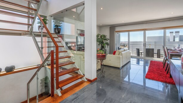A modern interior with a staircase, a living area, and a dining space.