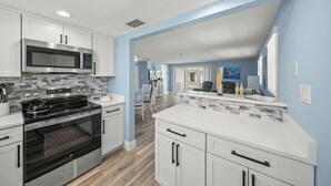 A modern kitchen with stainless steel appliances, white cabinetry, and a blue accent wall. - Island House Beach Resort V33 (Siesta Key)