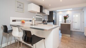 Una cocina moderna con armarios blancos, una isla central y taburetes de bar.