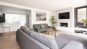 Una sala de estar moderna con un sofá gris, una mesa de centro y un televisor de pantalla plana montado en la pared.
