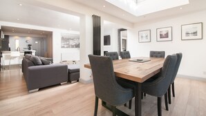 Una cocina moderna con una isla central, un comedor con mesa y sillas de madera, y una sala de estar con sofá y mesa de centro.