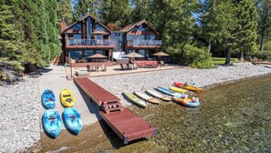 A lodge with a deck, kayaks, and a clear lake. - Lake Front Retreat With Your Private Beach & Hot Tub  (Tahoe Vista)