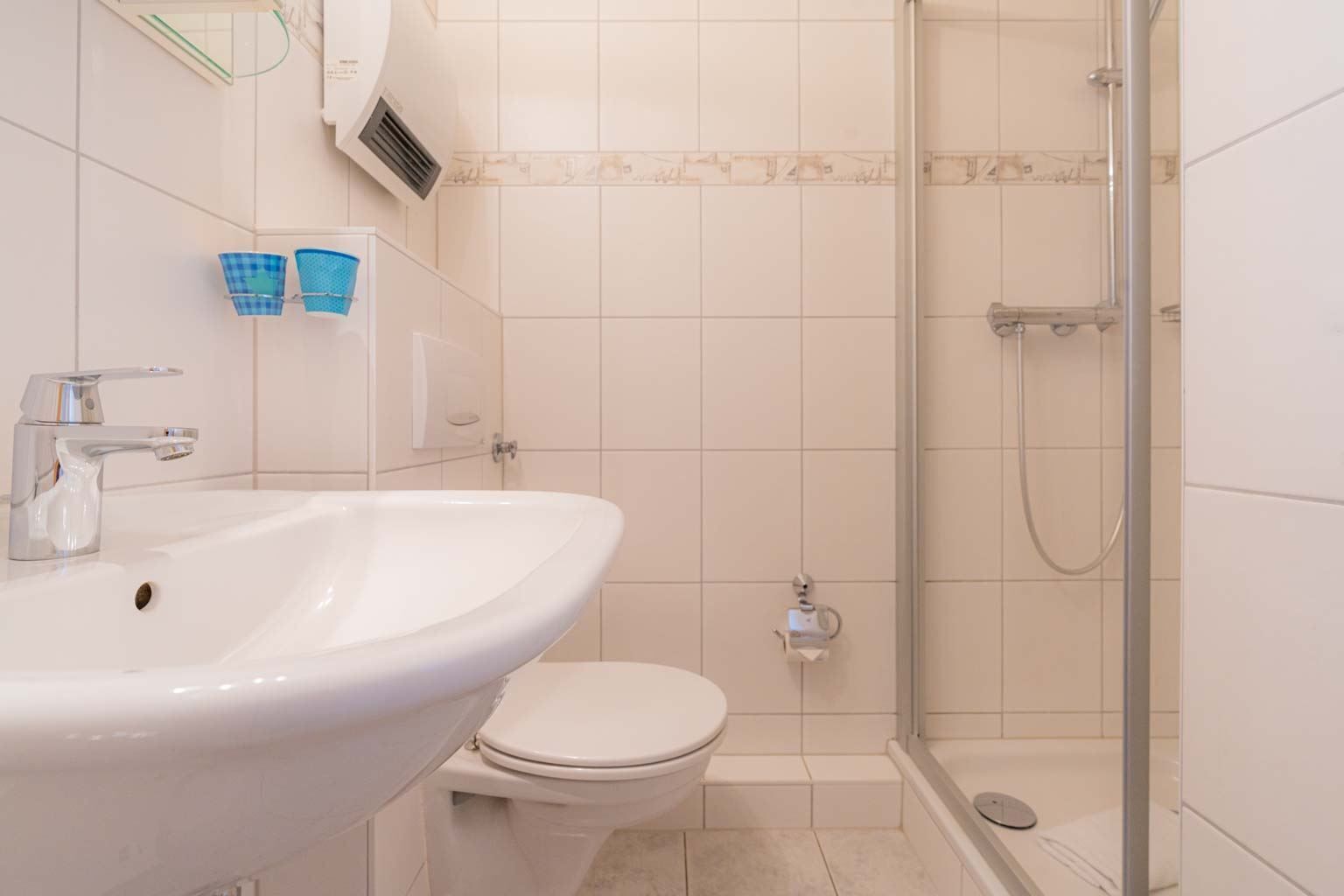 A bathroom with a white sink, toilet, and glass shower enclosure.