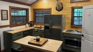 Una cocina con gabinetes de madera, un refrigerador de acero inoxidable, una cafetera y una cabeza de venado montada en la pared.