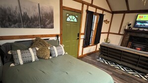 Un dormitorio con una cama grande, una puerta verde, una chimenea y un televisor en la pared.