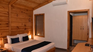 A wooden cabin bedroom with a bed, bedside table, and a wardrobe. - Sai River Resort (Khalapur)