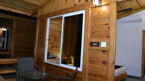 A wooden cabin with a large window, a small table with chairs, and a bunk bed. - Sai River Resort (Khalapur)