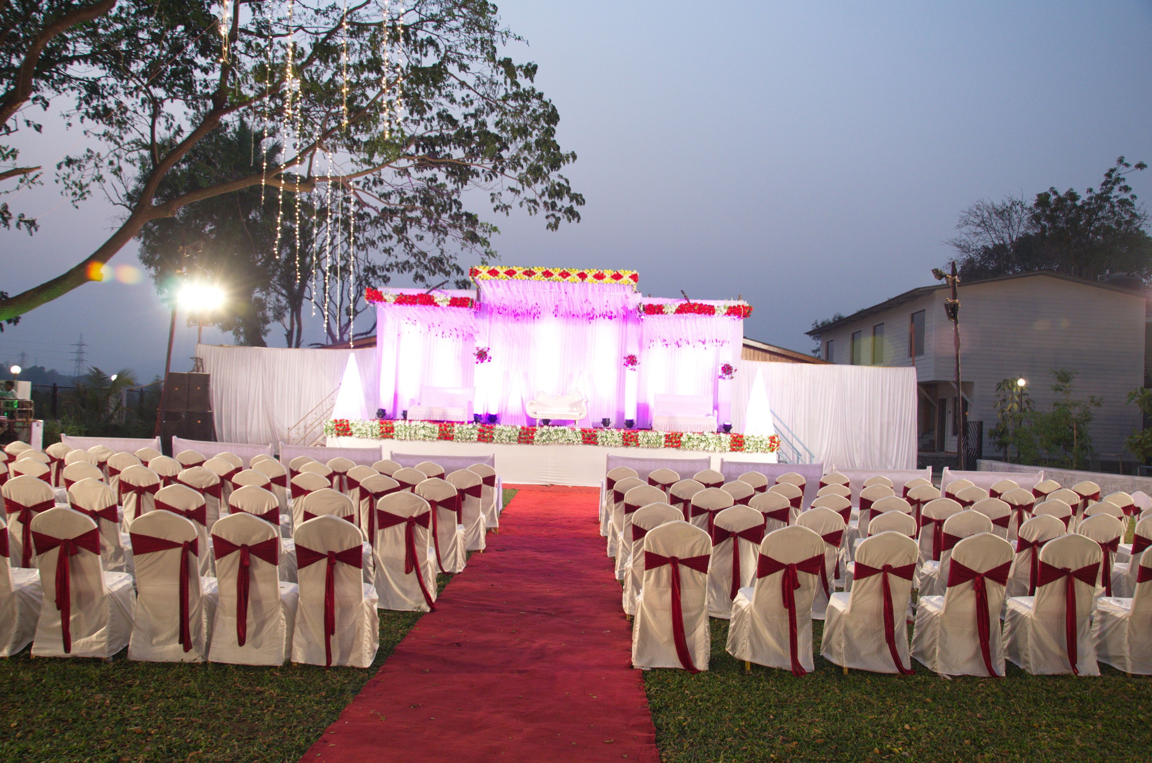An outdoor wedding venue with rows of chairs and a stage.