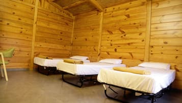 Two single beds with white linens and a green chair are positioned in this cozy room.