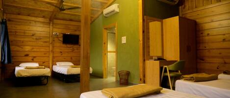 Una habitación tipo cabaña con dos camas, techo de madera, aire acondicionado y televisor en la pared.
