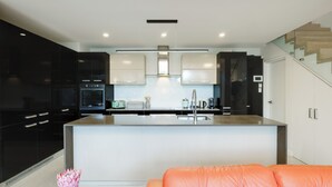 Een moderne keuken met zwarte kastjes, een centraal eiland en een heldere hanglamp.
