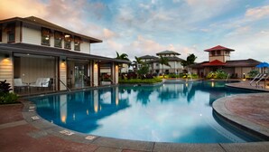 A swimming pool surrounded by buildings with outdoor seating and a clear sky.