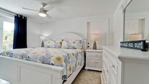 A bedroom with a bed, nightstands, a dresser, a ceiling fan, and a sign with words. - Poolside Relaxation Just Steps from the Gulf (Anna Maria)