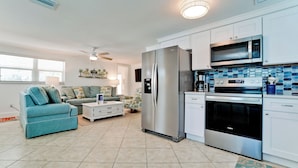 A modern kitchen with stainless steel appliances, a white countertop, and a blue patterned backsplash. - Poolside Relaxation Just Steps from the Gulf (Anna Maria)
