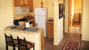 Eine kompakte Küche mit Mikrowelle, Kühlschrank und einem Essbereich mit Tisch und Stühlen.