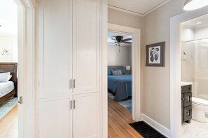 Un couloir mène à une chambre qui comprend un lit, une armoire et une salle de bain avec douche.
