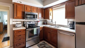 A modern kitchen with wooden cabinets, stainless steel appliances, and a window providing natural light.