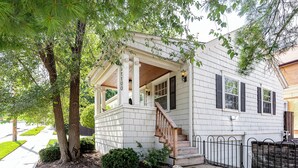 A two-story house with a covered porch, a staircase, and a fenced yard.