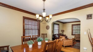 A dining area with a wooden table, chairs, potted plants, and a chandelier.