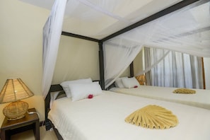 Ein Hotelzimmer mit einem Bett, das unter einem Baldachin steht, einer Nachttischlampe und einem dekorativen Gegenstand auf dem Bett.