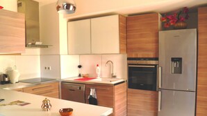 Een moderne keuken met een centraal eiland, roestvrijstalen apparatuur en houten kastjes.