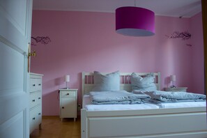 Une chambre à coucher avec un lit, des tables de chevet, une commode et une lampe suspendue.