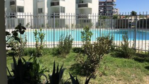 Un immeuble résidentiel doté de nombreux balcons, d’une piscine et d’un espace clos aménagé en jardin.