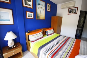 A bedroom with a bed, a nightstand with a lamp, and a wardrobe. - Summer Breeze Inn Hotel (Wichit)