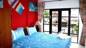 A bedroom with a bed, a wooden wardrobe, a window with curtains, and a painting on the wall. - Summer Breeze Inn Hotel (Wichit)