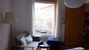 A cozy living room with a sofa, a small table with a tray, a lamp, and a view of the outside. - Cozy inner city apartment: City escape Lüneburg (Lüneburg)