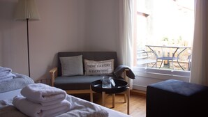 A hotel room with a bed, a small table with a tray, a sofa with a pillow, a lamp, and a window with a view of the outside. - Cozy inner city apartment: City escape Lüneburg (Lüneburg)