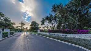 A road leading to a gated entrance with a sign reading "Kuilima Estates West".