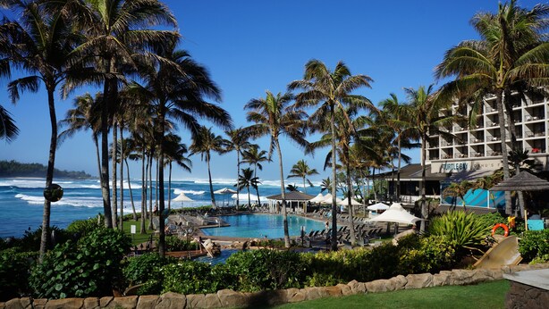 A resort with a pool, palm trees, and ocean views.