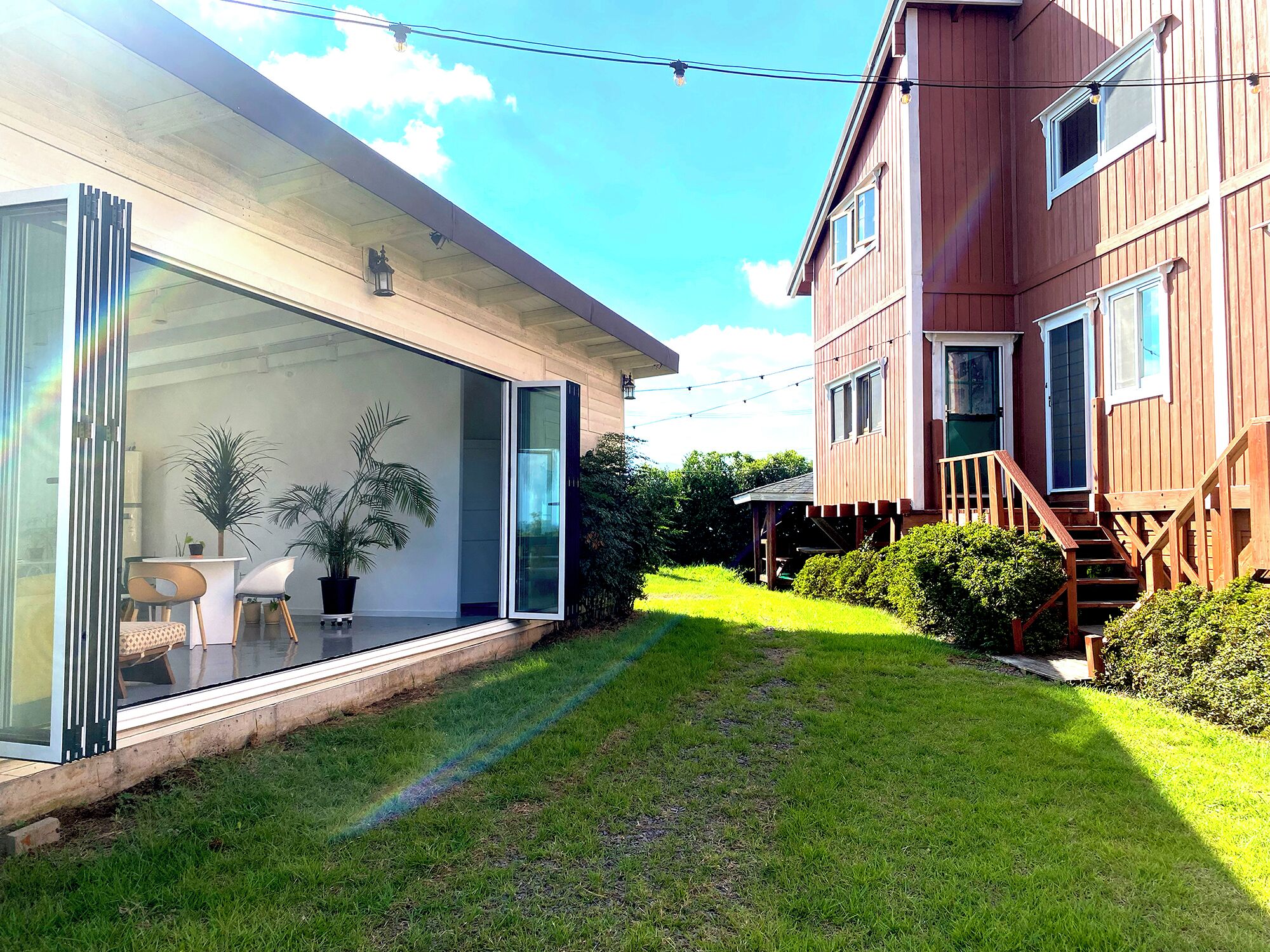 Een modern huis met een glazen deuropening, een houten terras en een verzorgd gazon.