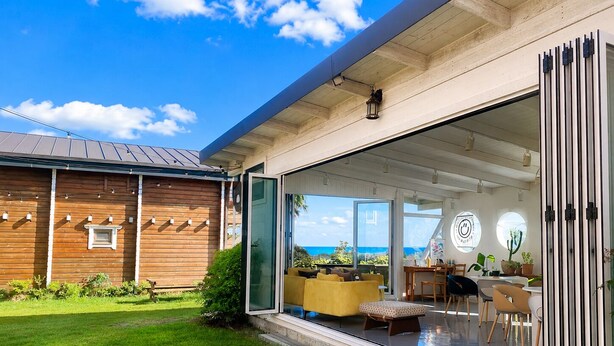 Una casa moderna con un amplio ventanal corredera que da a una sala de estar con vista al océano.