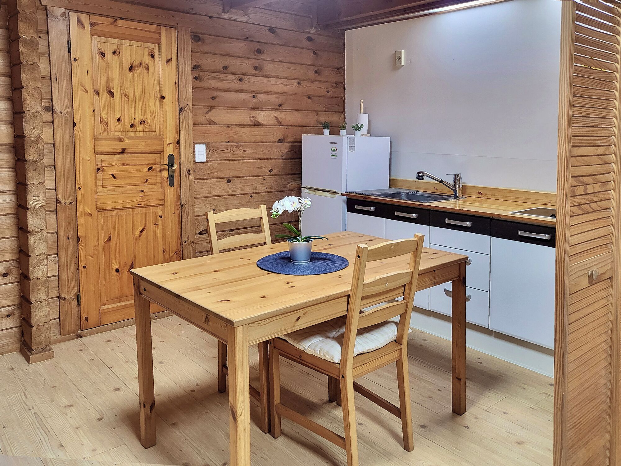 Un interior de madera con una mesa de comedor, sillas, un refrigerador y un lavamanos.