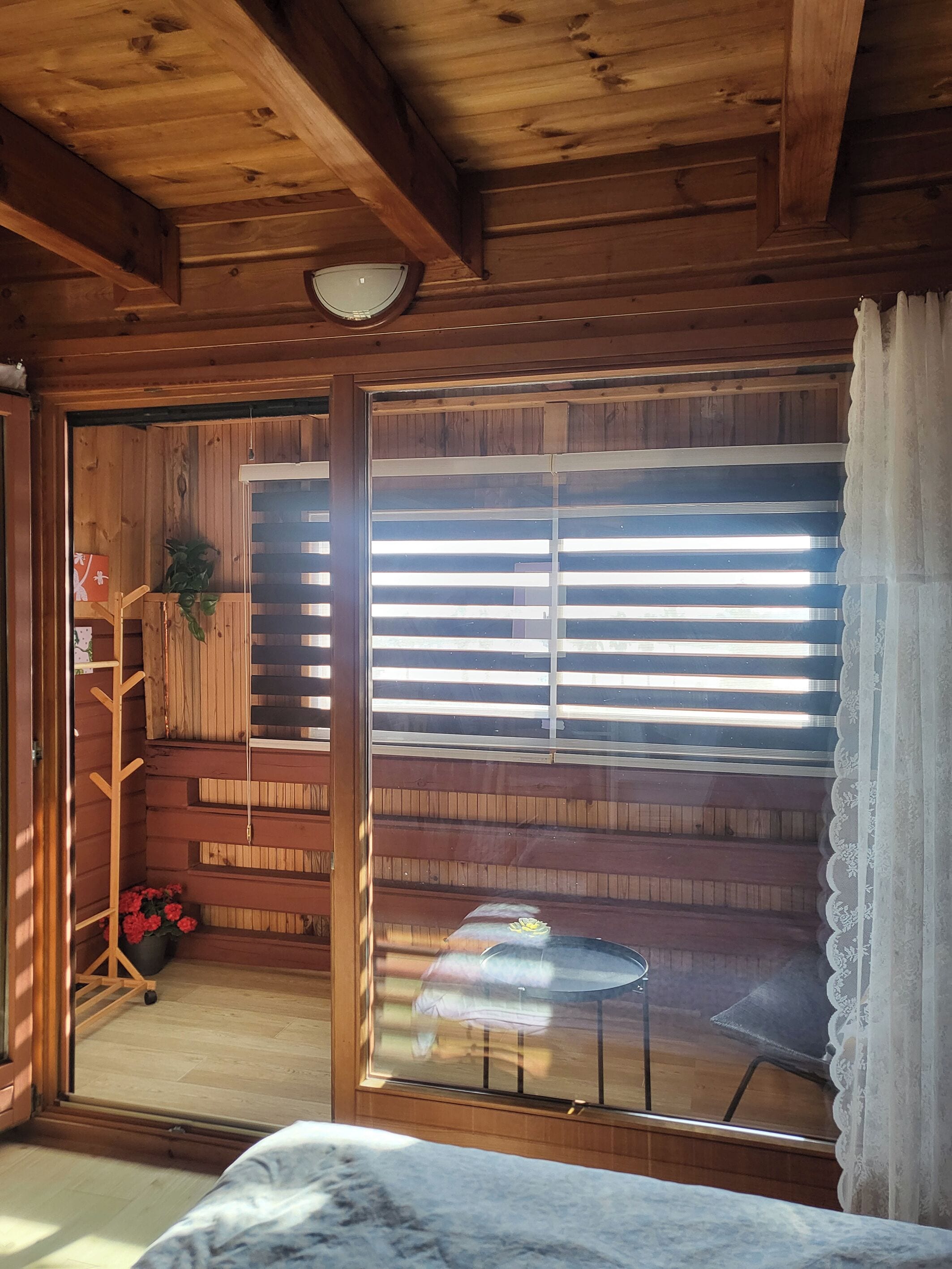 A wooden cabin interior with a sliding glass door, a small table, and a chair.