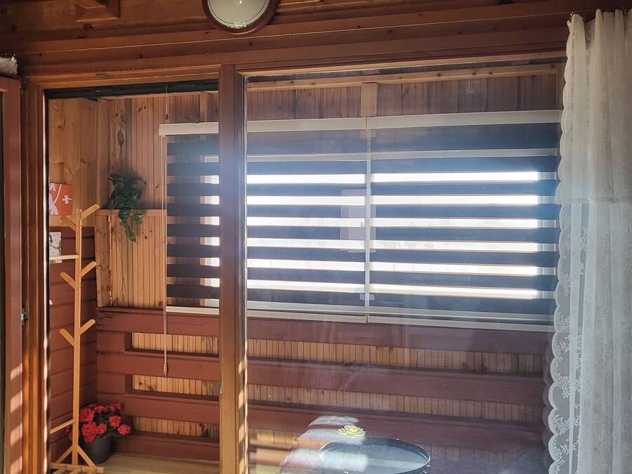 A wooden cabin interior with a sliding glass door, a small table, and a chair.