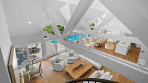 A modern interior with a dining area, kitchen, and a view of a swimming pool. - Bay Breeze Escape—Pool, Game Room & Views (Centerville)