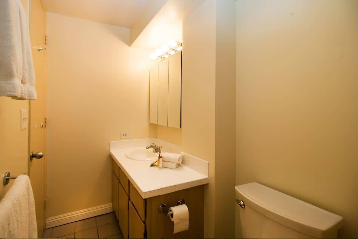 A bathroom with a sink, mirror, toilet, and towel rack.