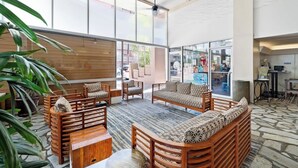 A spacious lobby with wooden furniture, large windows, and a stone floor. - Beachside escape w/ ocean view, 22nd floor (Honolulu)