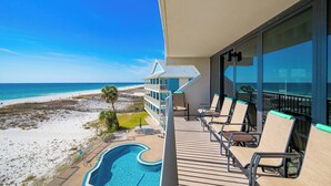Ein Balkon mit Blick auf Strand und Meer, Liegestühle und ein Pool.
