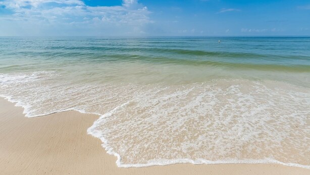 Ein Strand mit klarem Wasser und sandigem Ufer.