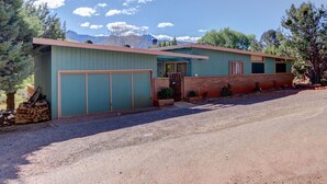 Una casa de dos pisos con garaje, puerta principal y un pequeño porche.