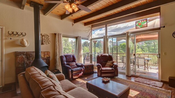 Una sala de estar acogedora con chimenea, sillones de cuero, un sofá y un amplio ventanal corredera que da a una terraza exterior.