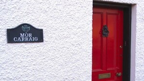 Une porte rouge avec une enseigne noire au-dessus, sur laquelle on peut lire « MOR CARRAIG ».