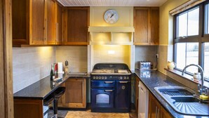Une cuisine avec des meubles de rangement en bois, une cuisinière, un évier et une fenêtre.