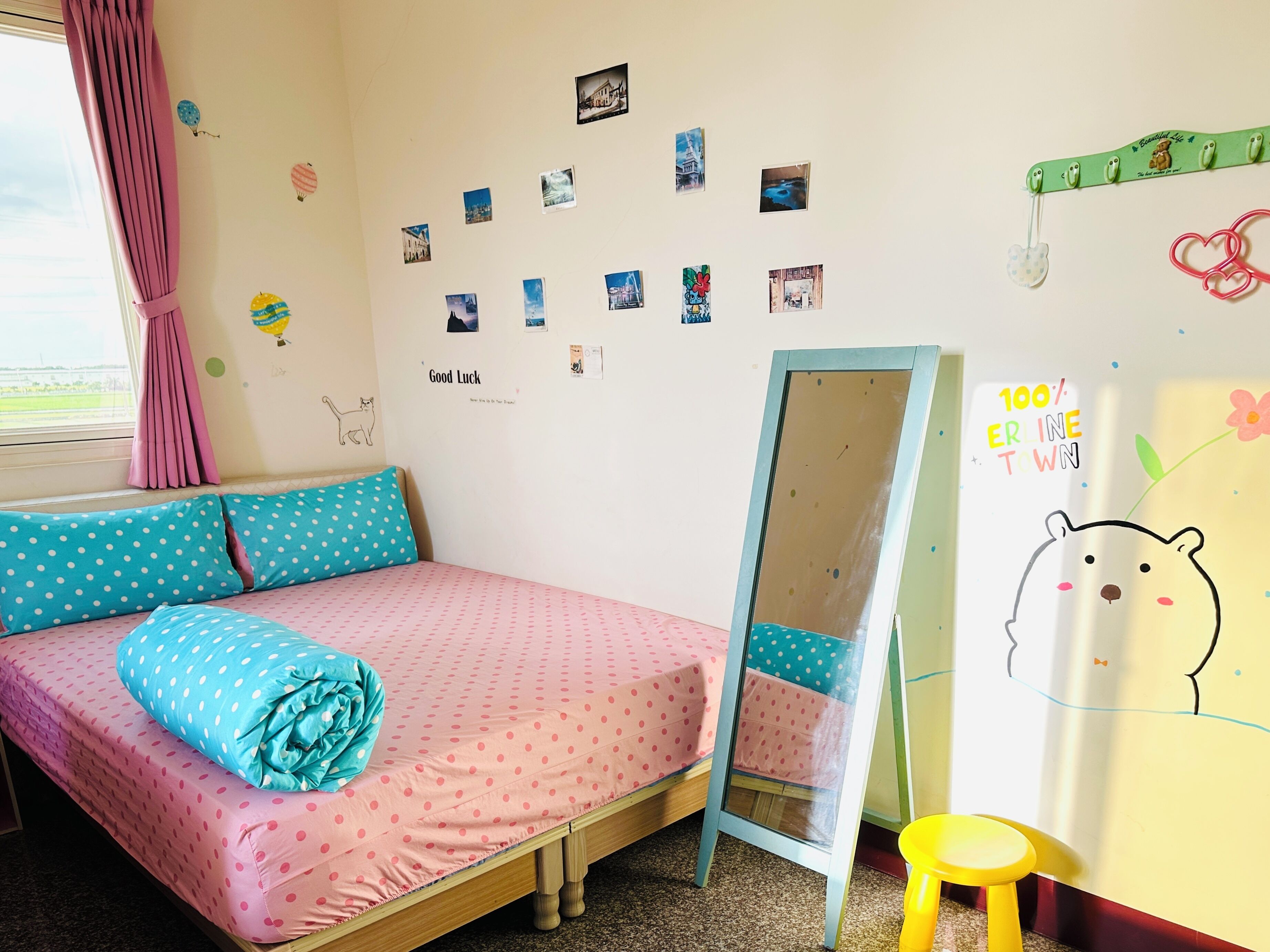 A bedroom with a bed, a mirror, and a wall decorated with photos and drawings.
