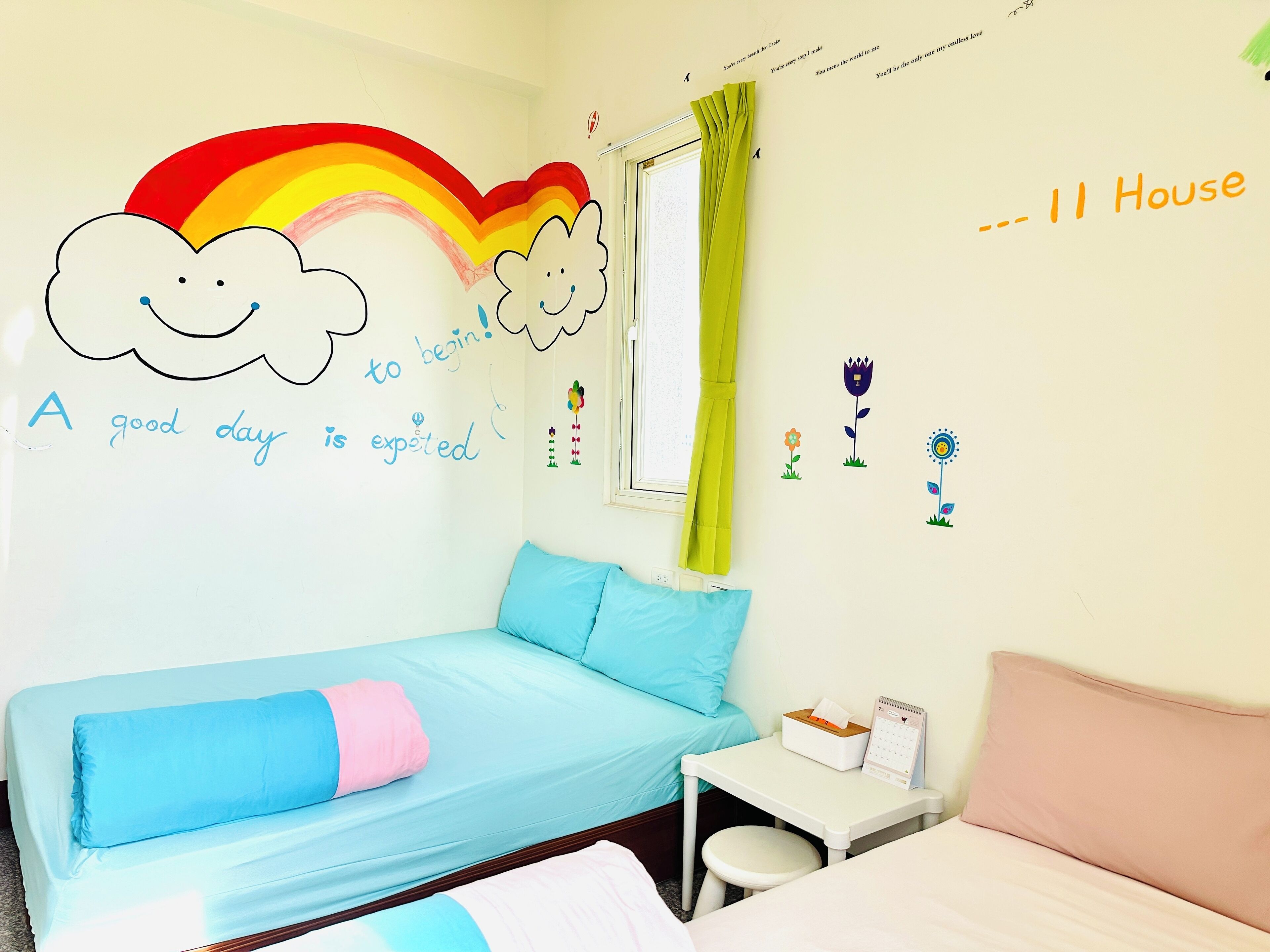 Un dormitorio infantil con una cama, una mesita y una ventana con cortinas.