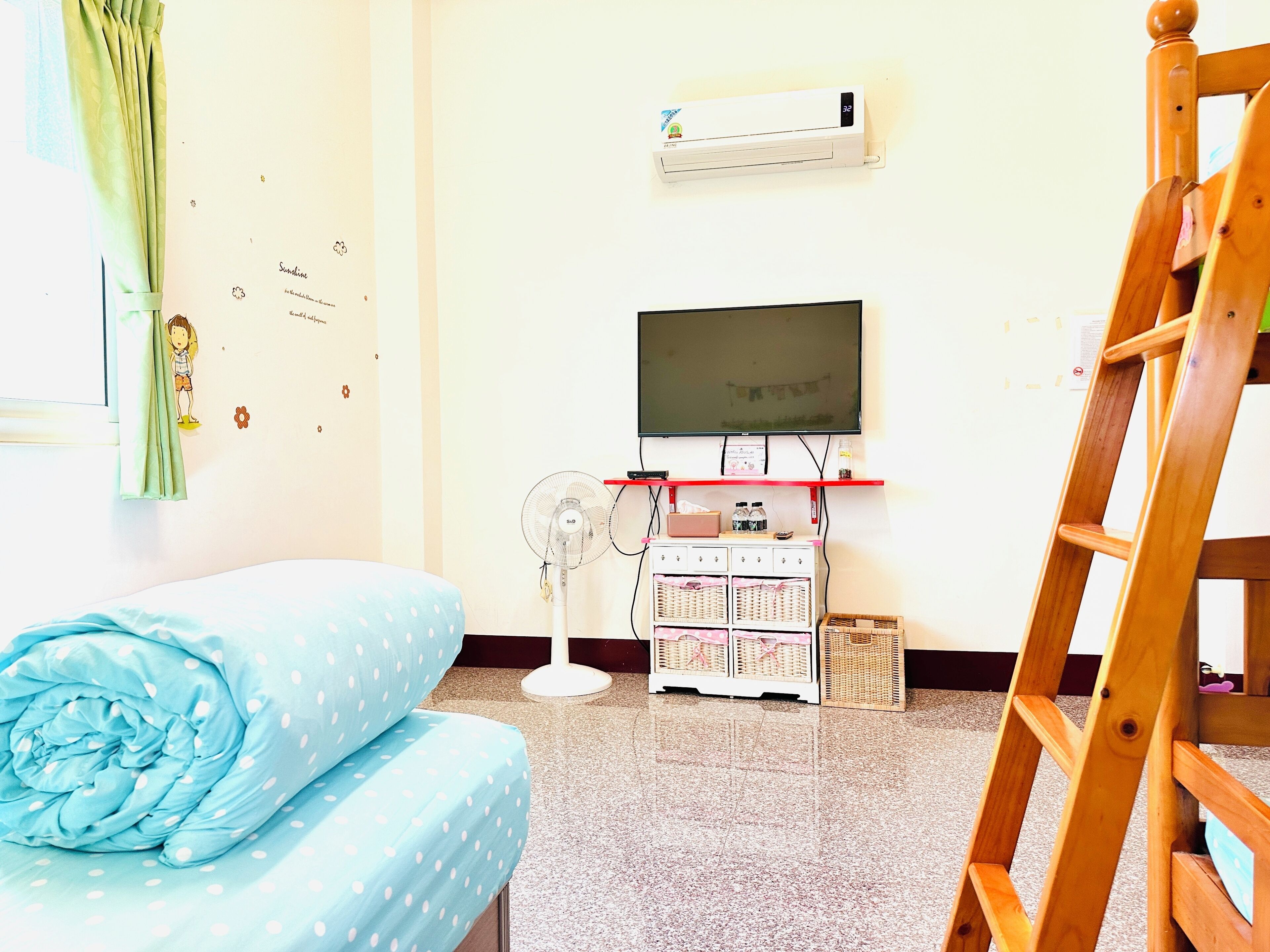 Una habitación con cama, televisión, aire acondicionado, ventilador y una escalera de madera.